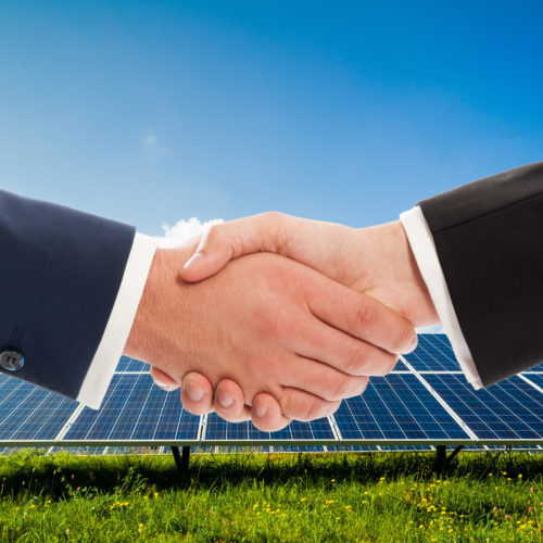 Businessmen handshake on solarpower photovoltaic panel background as bio-energy business team agreement
